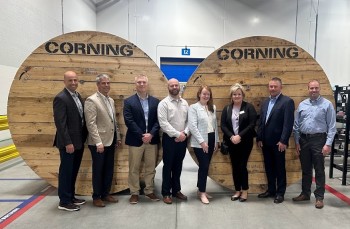 Group of professionals standing together in front of huge wooden spools