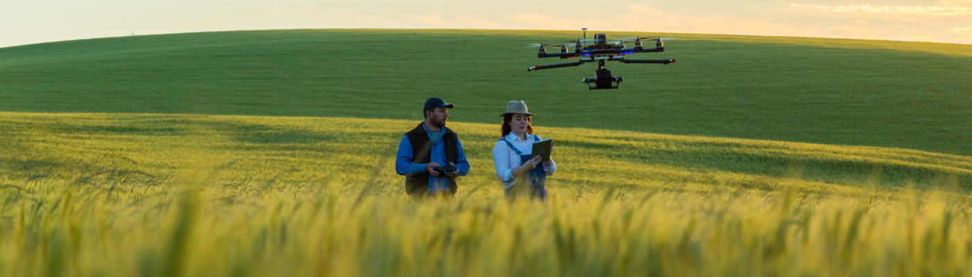Two people controlling a drone in a rural field