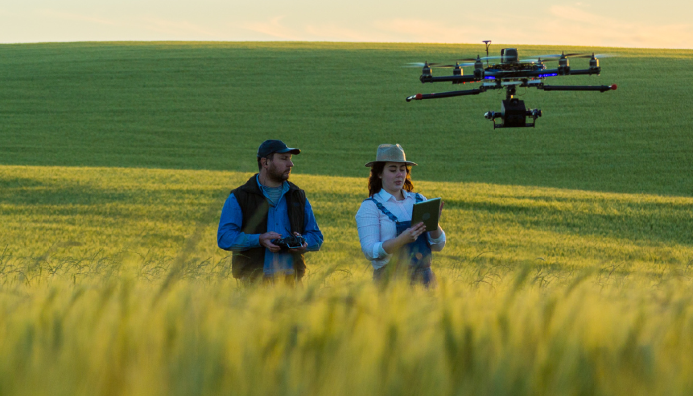 Two people controlling a drone in a rural field