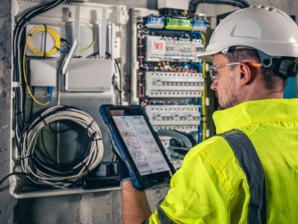 An electrical technician working in a switchboard with fuses.